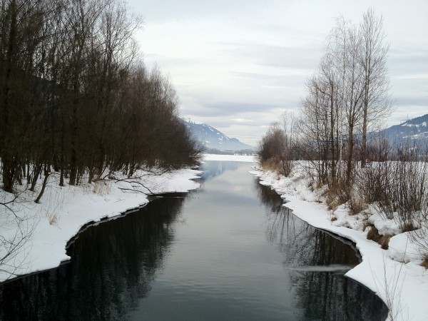Ein winterlicher Fluss mit leicht vereisten Ufern und Schnee am Flußrand